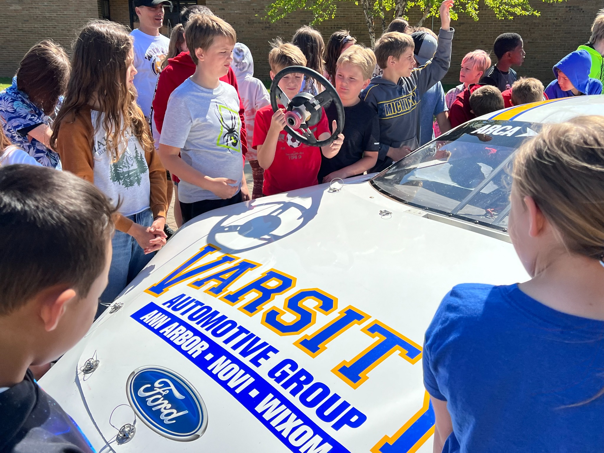 Students examining the steering wheel of the race car
