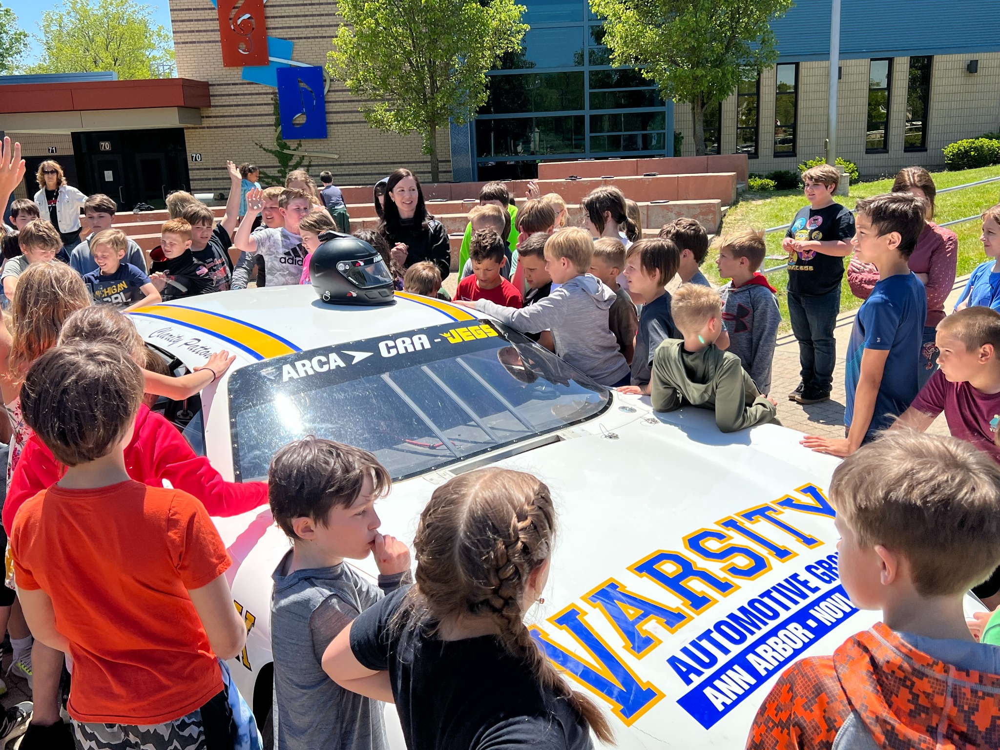 Students gathered around a race car during a school visit